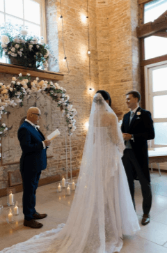 Stephen Pestell conducting a wedding ceremony for a couple beneath a floral arch
